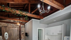 Amplia sala de estar con un sofá grande, una mesa de centro de madera y una cocina con armarios blancos.