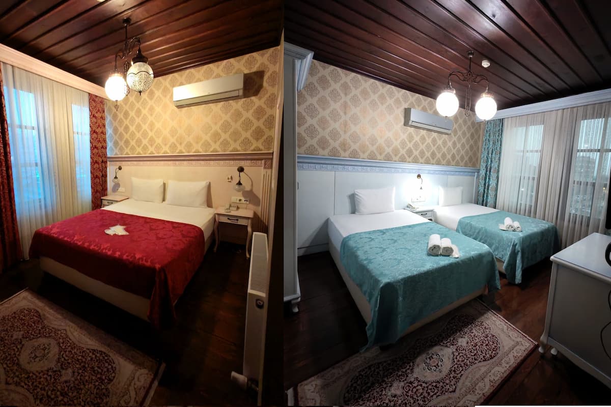 A hotel room with a large bed, a smaller bed, a desk, and a wardrobe.