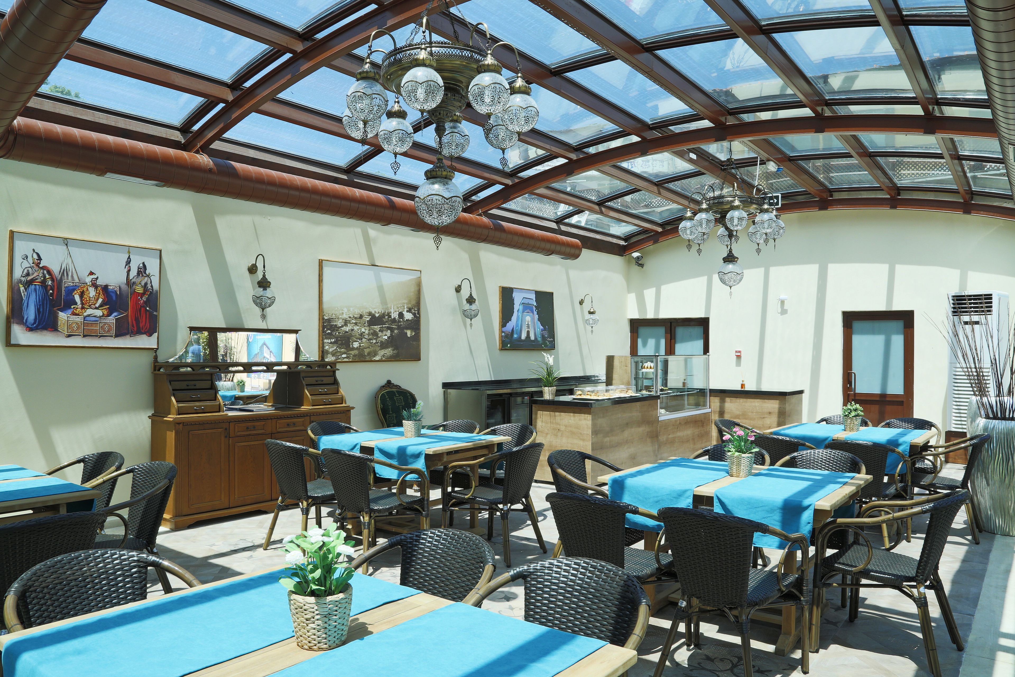 A restaurant with a glass ceiling, wicker furniture, and blue tablecloths.