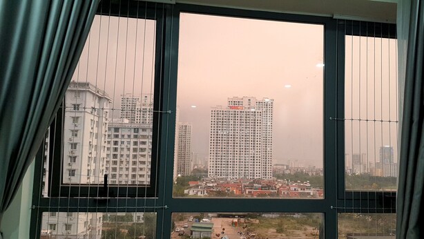 A view through a window with curtains, featuring high-rise buildings and a hazy sky. - EQC Hotel 518 (Seattle)