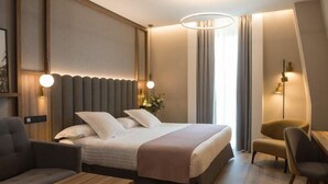 Una habitación de hotel moderna con una cama grande, un escritorio, una silla y un sofá.