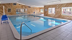 Una piscina interior con una pared de madera, una silla de salvavidas y un letrero de precaución.