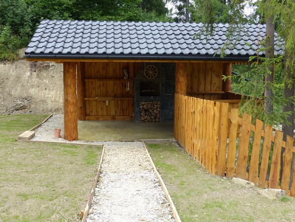A wooden cabin with a tiled roof, a stone fireplace, and a gravel path leading to the entrance. - Domek Pod Howyzem (Lapsze Nizne)