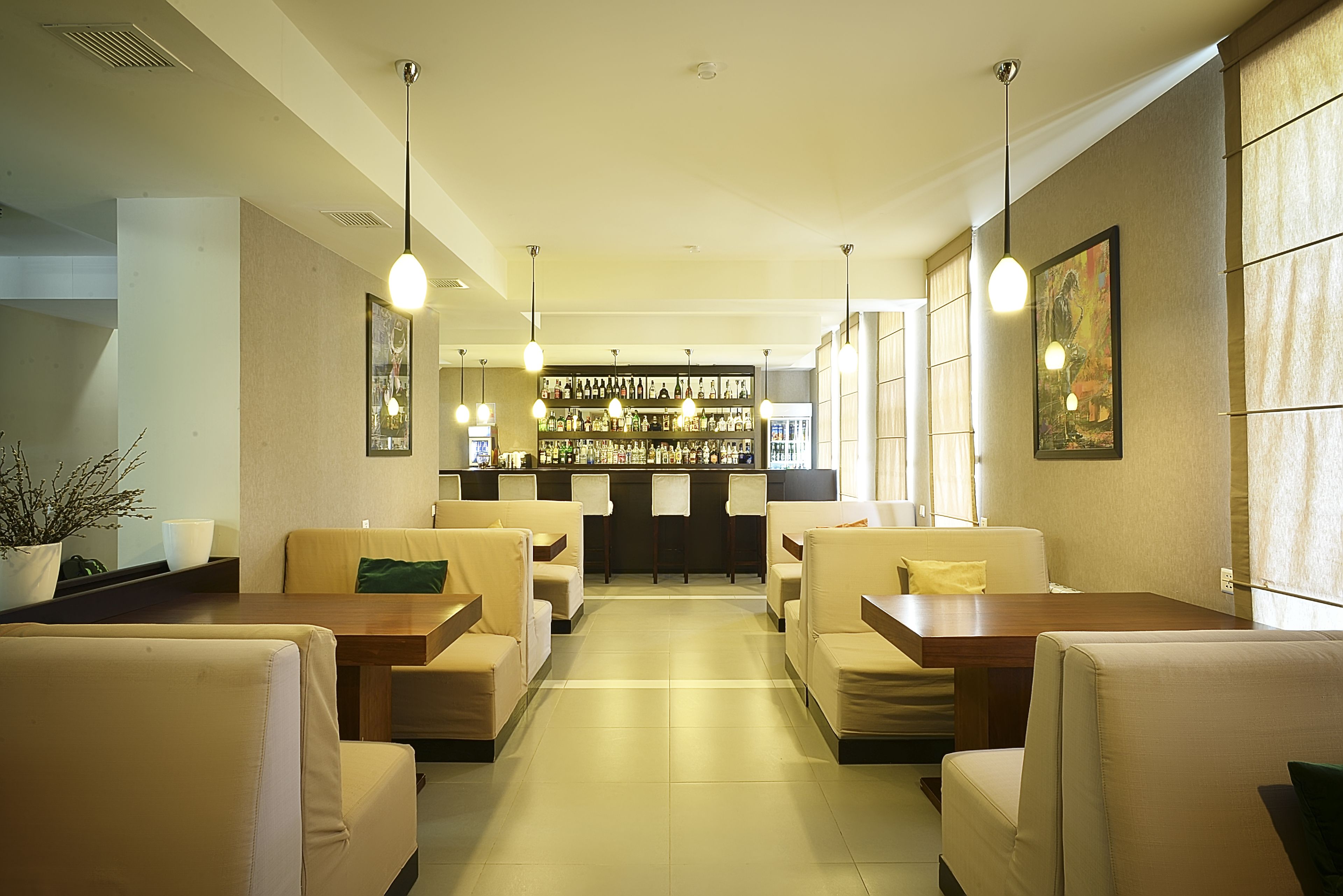 A hotel lobby with seating areas, a bar, and a display of bottles.