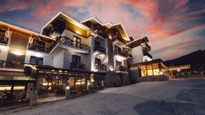 Un hôtel à plusieurs étages doté de balcons, d’un restaurant et d’une façade en pierre.