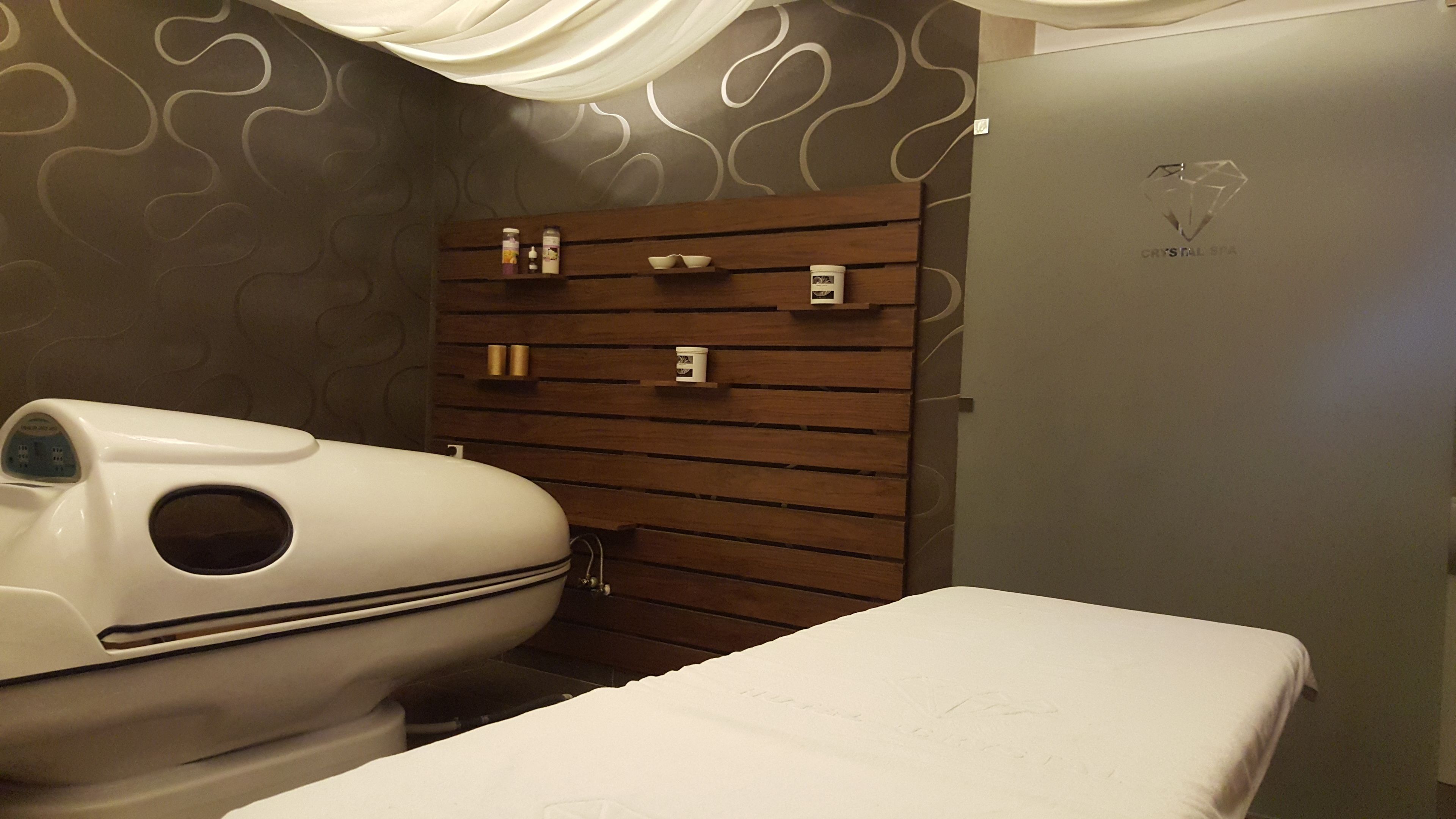 Une salle de spa équipée d’une douche à vapeur, d’un mur revêtu de panneaux en bois et d’un lit.
