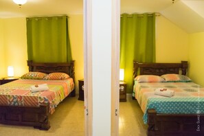 Two identical twin beds with green curtains, wooden headboards, and bedside lamps.
