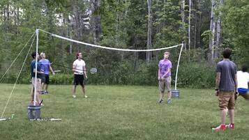 Un grupo de personas jugando bádminton al aire libre, con una red y volante en el suelo.