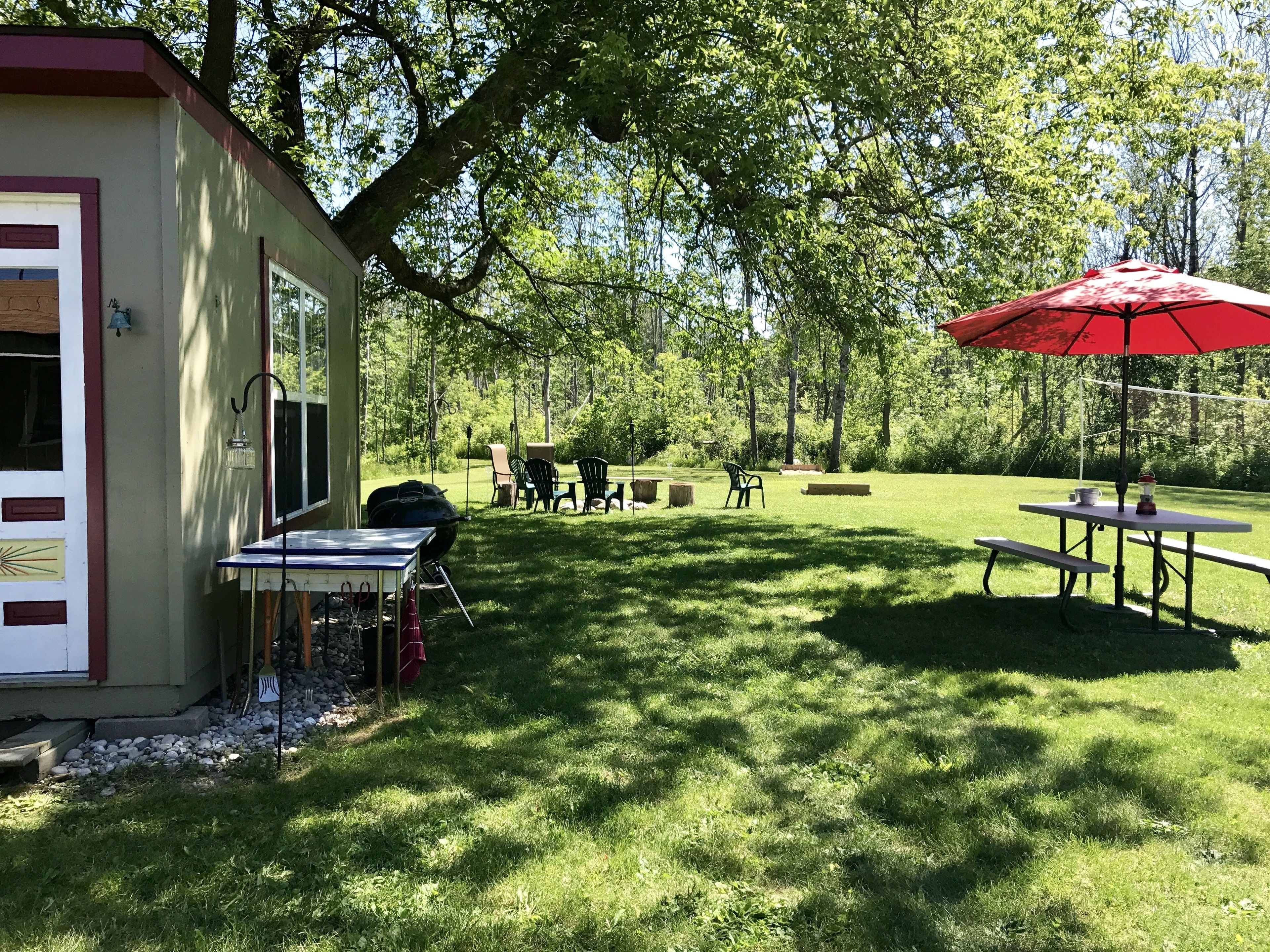 A patio area with a grill, outdoor seating, and a red umbrella.