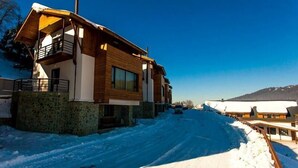 A modern building with a wooden facade, a balcony, and a snow-covered landscape. - Crystal Hill Villas (Borjomi)
