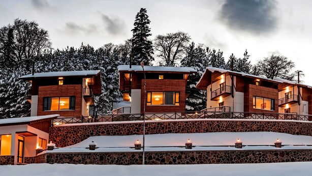A multi-story lodge with a stone facade, wooden balconies, and snow-covered surroundings. - Crystal Hill Villas (Borjomi)