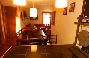A dining area with a table and chairs, a sofa, and a lamp. - Blue Frost Apartments (Lake Placid)