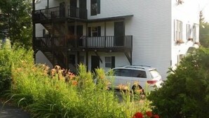 A multi-story building with balconies and a car parked in front. - Blue Frost Apartments (Lake Placid)