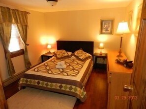 A hotel room with a bed, two bedside tables with lamps, a window with curtains, and a door.
