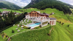 Un hotel grande con piscina, rodeado de colinas y montañas verdes exuberantes.