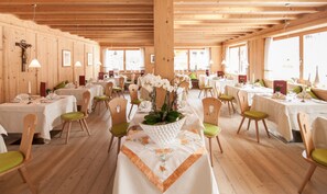 A restaurant with wooden interiors, multiple tables, and chairs.