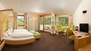 Ein Hotelzimmer mit Bett, Schreibtisch mit Fernseher, Stuhl und Blick ins Freie.