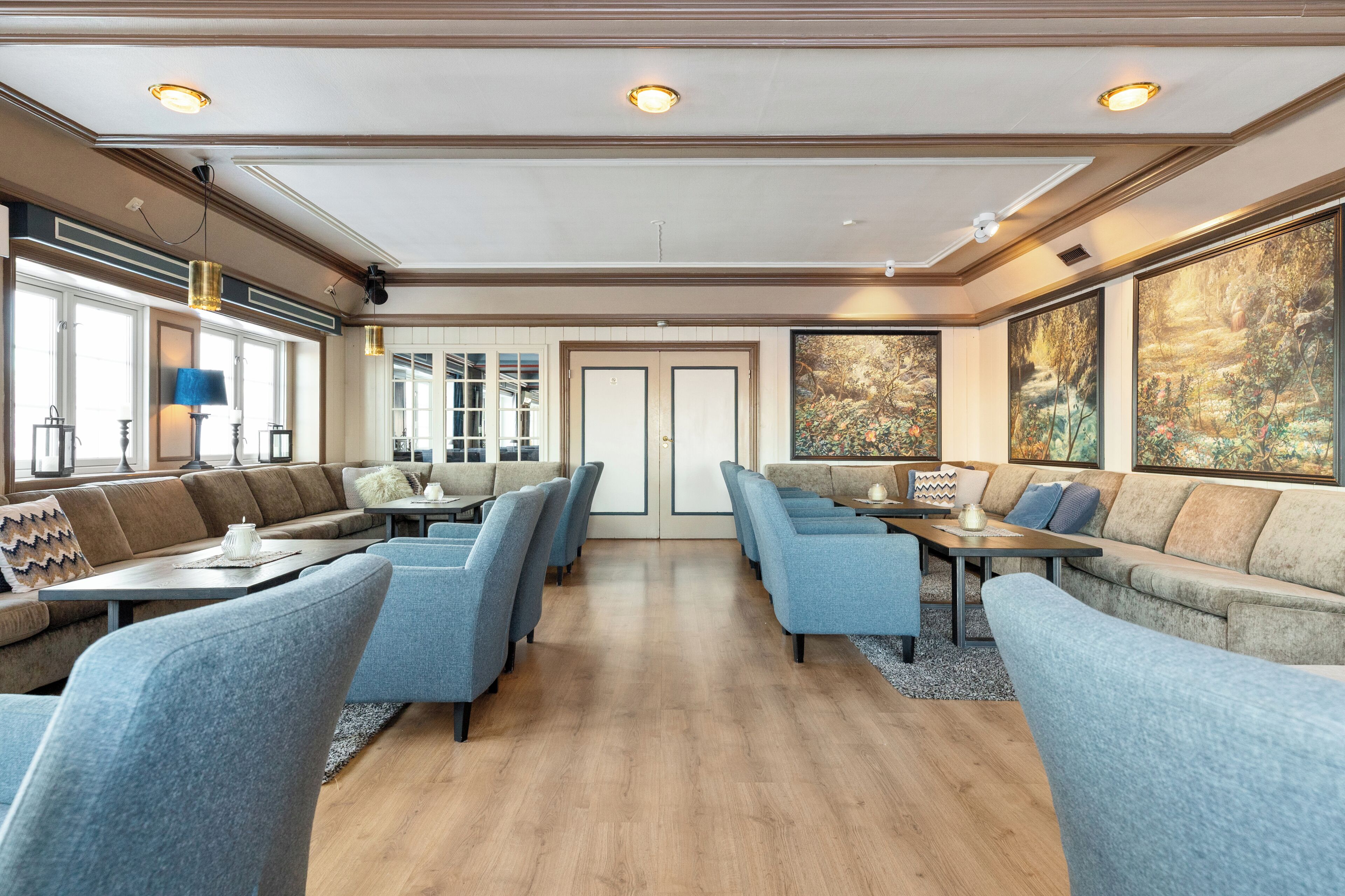 A hotel lobby with a central seating area, large windows, and artwork on the walls.