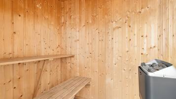 Een houten sauna met een bank en een prullenbak.