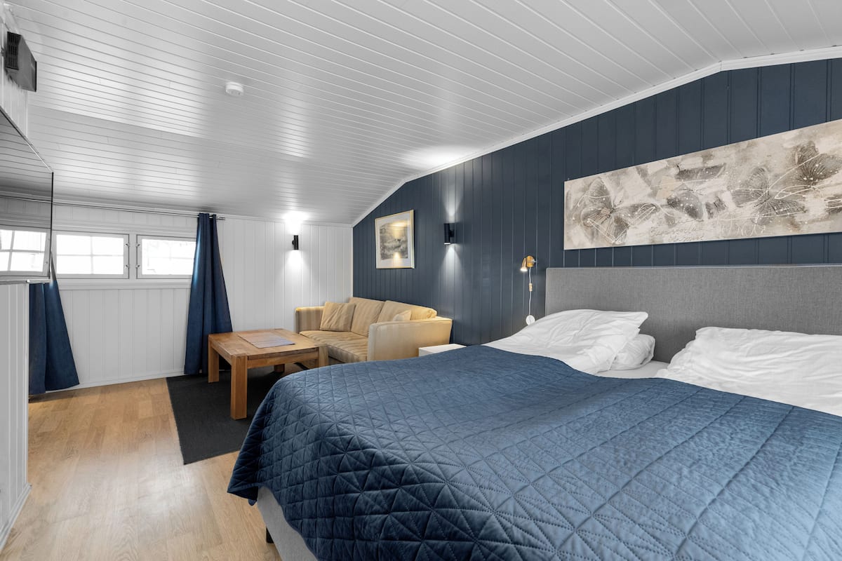 Een slaapkamer met een bed, een bank, een tafel en een schilderij aan de muur.