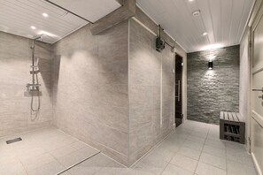Une salle de bain moderne avec une douche, des murs carrelés et un mur d’accent en pierre.