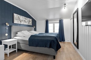 Een slaapkamer met een bed, nachtkastje en een grote spiegel.