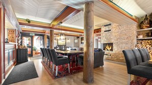 A spacious dining area with a wooden table and chairs, a fireplace, and a stone wall. - Gomobu Fjellstue (Vestre Slidre)