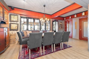 A dining area with a chandelier, wooden flooring, and a red accent wall. - Gomobu Fjellstue (Vestre Slidre)