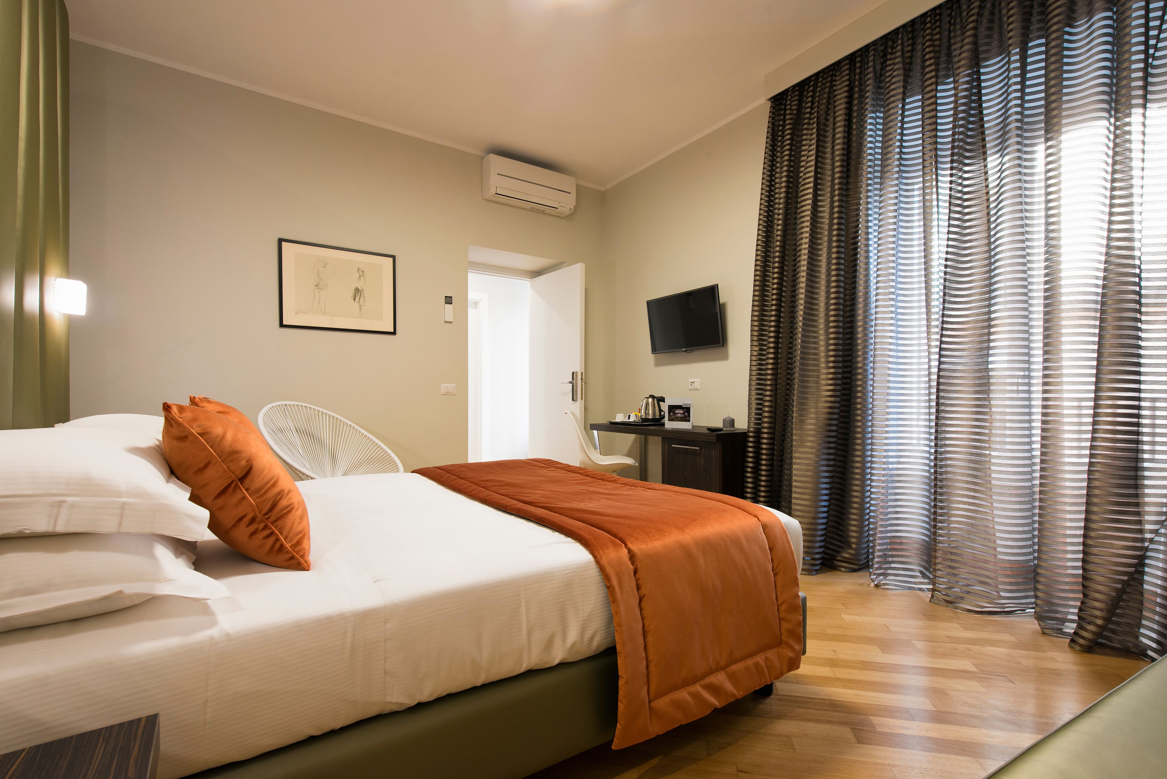 Een hotelkamer met een bed, een bureau, een televisie en gordijnen.