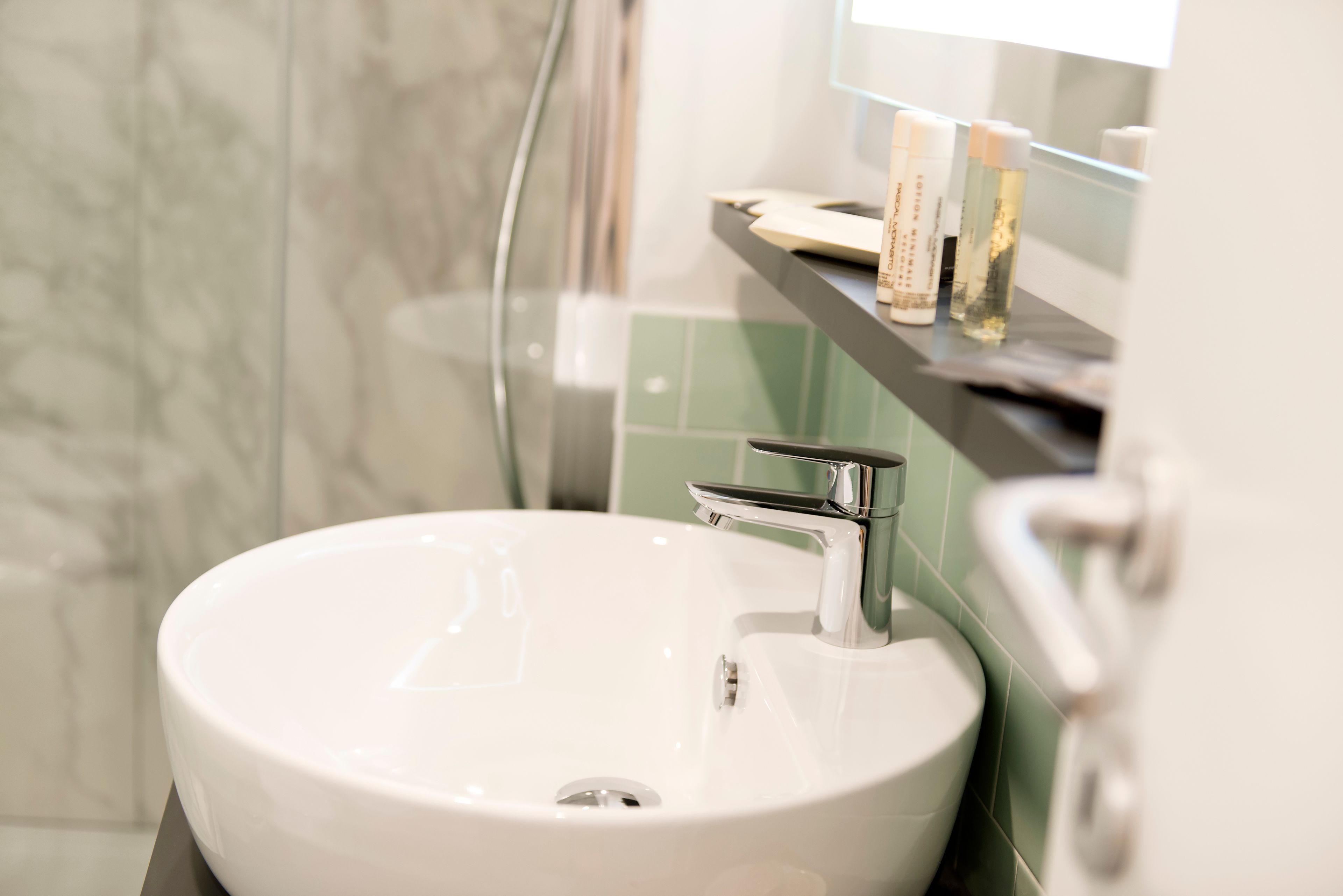 A bathroom with a white sink, chrome faucet, and a mirror above it.