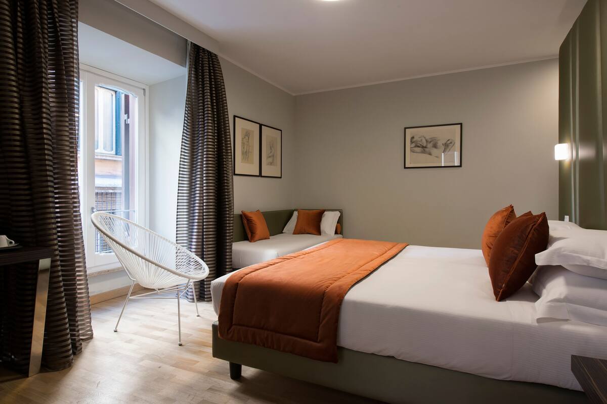 Un dormitorio moderno con una cama grande, dos almohadas, una silla y obras de arte en las paredes.
