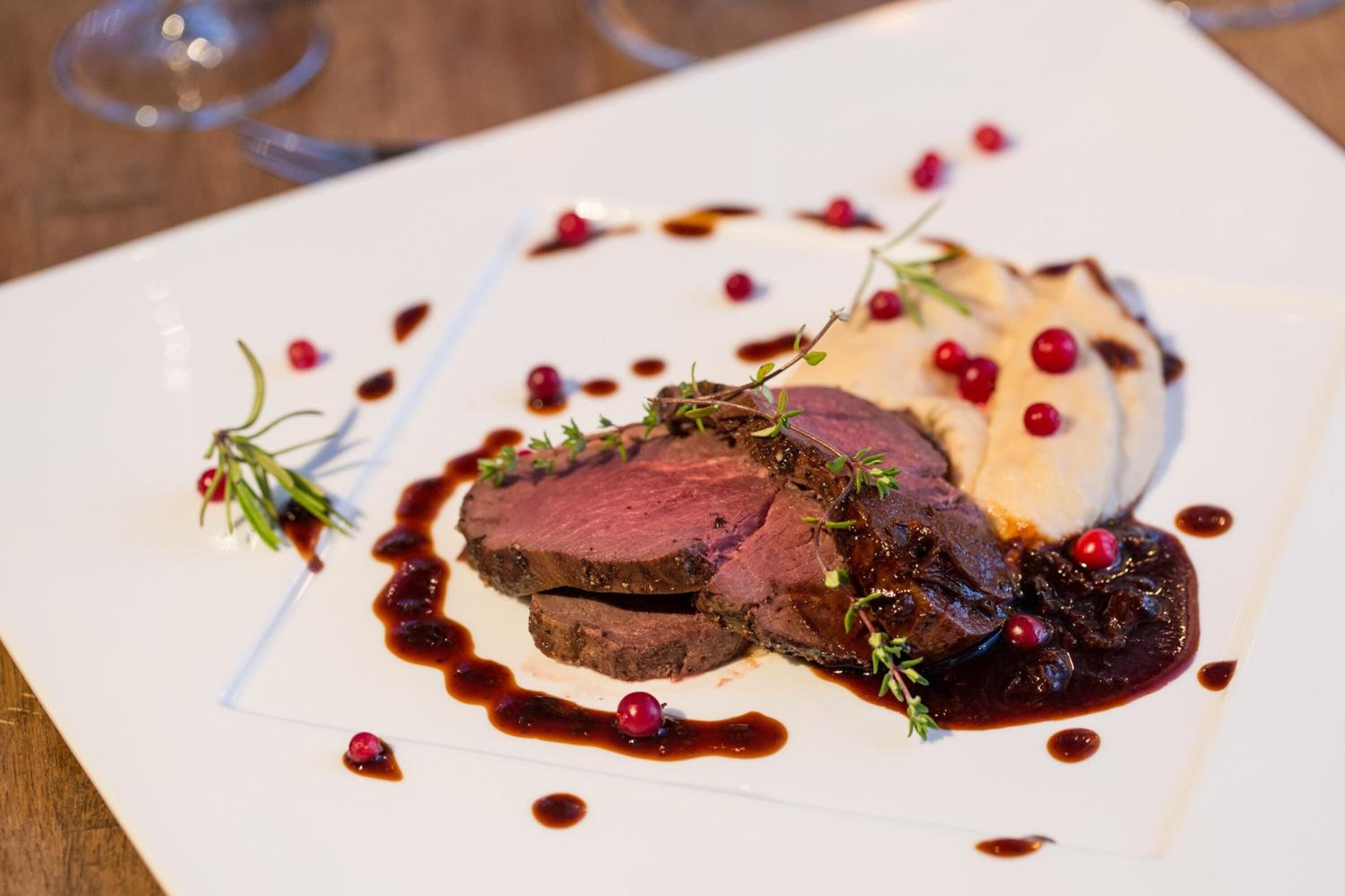 A plate of food with meat, berries, and sauce.