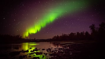 A night sky with the Northern Lights over a calm body of water reflecting the lights.