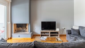 A modern living room with a fireplace, a flat-screen TV, a sofa, and a coffee table. - Elvita Spata Luxurious Villa (Spata-Artemida)