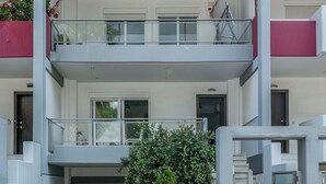 A modern multi-story building with a central staircase, balconies, and a gated entrance. - Elvita Spata Luxurious Villa (Spata-Artemida)