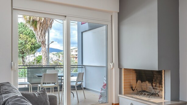 A modern living room with a grey sofa, a glass coffee table, and a fireplace. - Elvita Spata Luxurious Villa (Spata-Artemida)