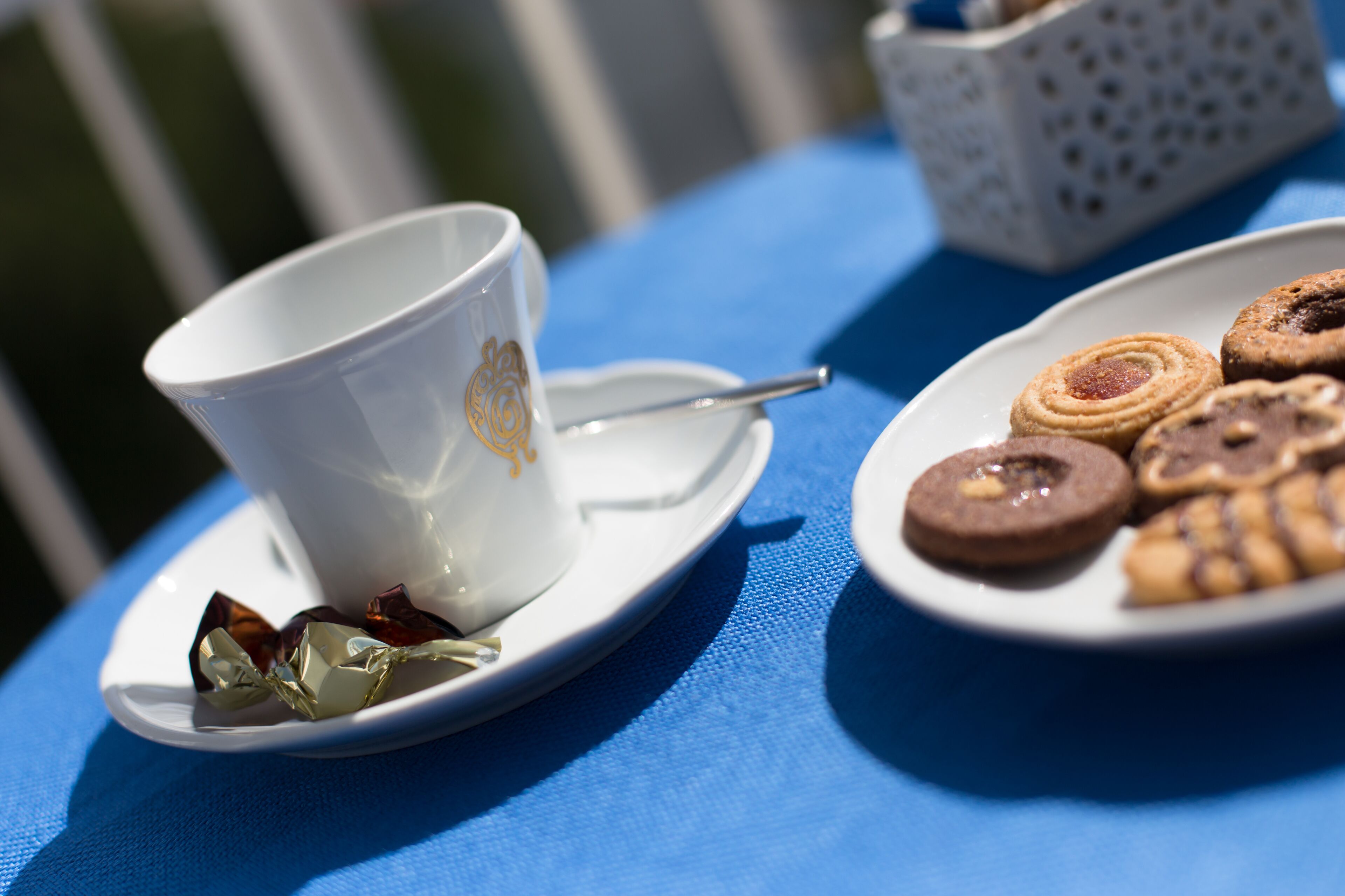 Un tavolo con una tazza e un piattino, un cucchiaino e un piatto con dei biscotti.