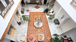 Pátio interno com piso estampado, áreas de estar e plantas em vasos.