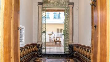 A hallway with patterned floor tiles, wooden doors, and a decorative ceiling light.