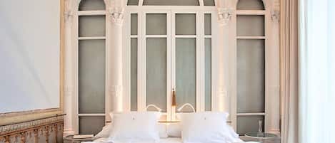 Et hotelværelse med en stor seng, detaljerede vinduesrammer og et klassisk design.