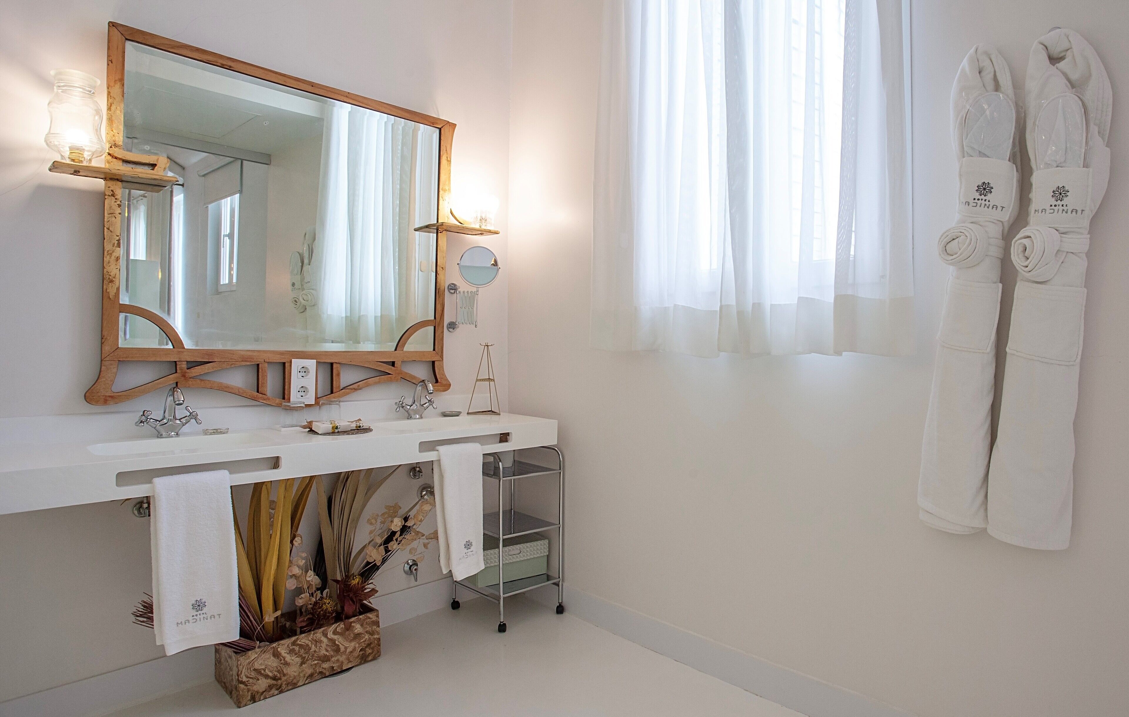 Ein Badezimmer mit einem spiegelnden Holzbettrahmen, einem weißen Waschbecken und einem Handtuchhalter mit Handtüchern.
