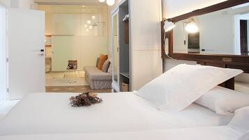 A hotel room with a bed, a wardrobe, a mirror, and a bathroom visible through an open door.