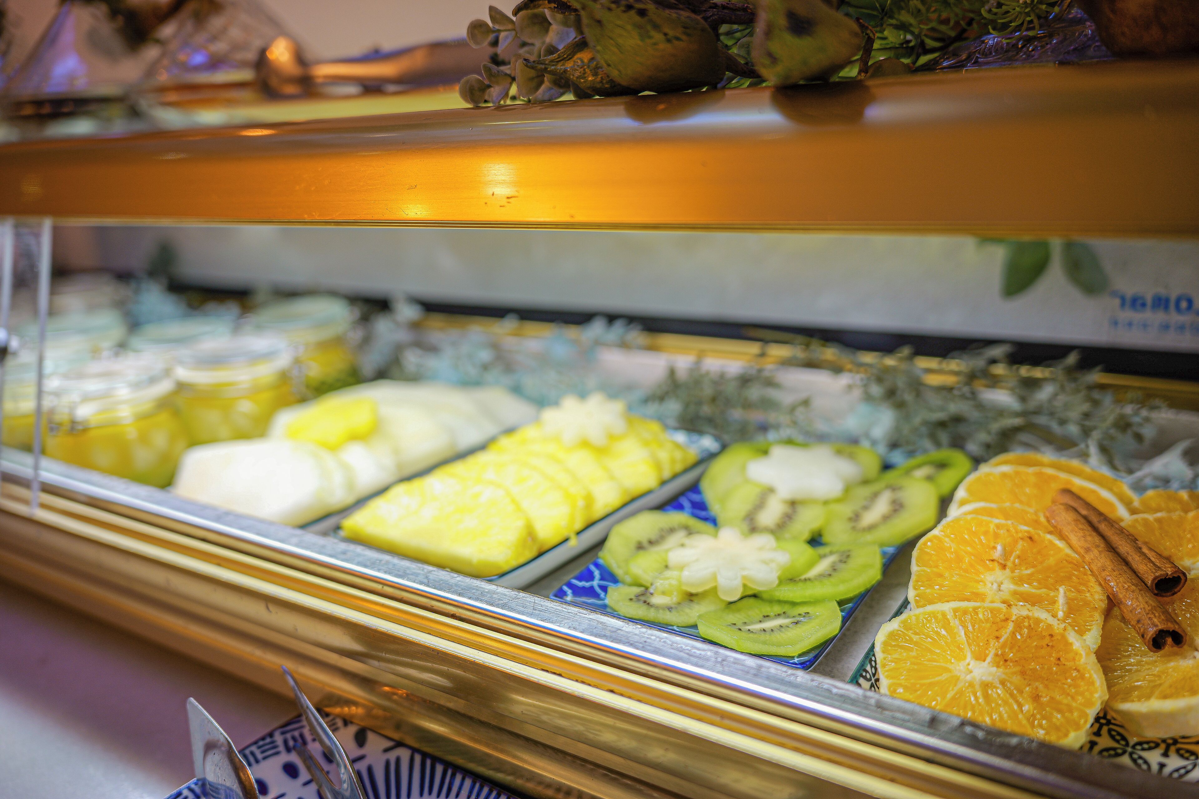 Una vitrina con diversas frutas, como piña, kiwi y gajos de naranja.