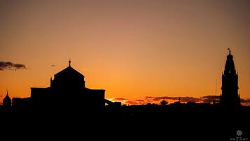 A silhouette of a cityscape at sunset with prominent buildings, including a church and a tower.