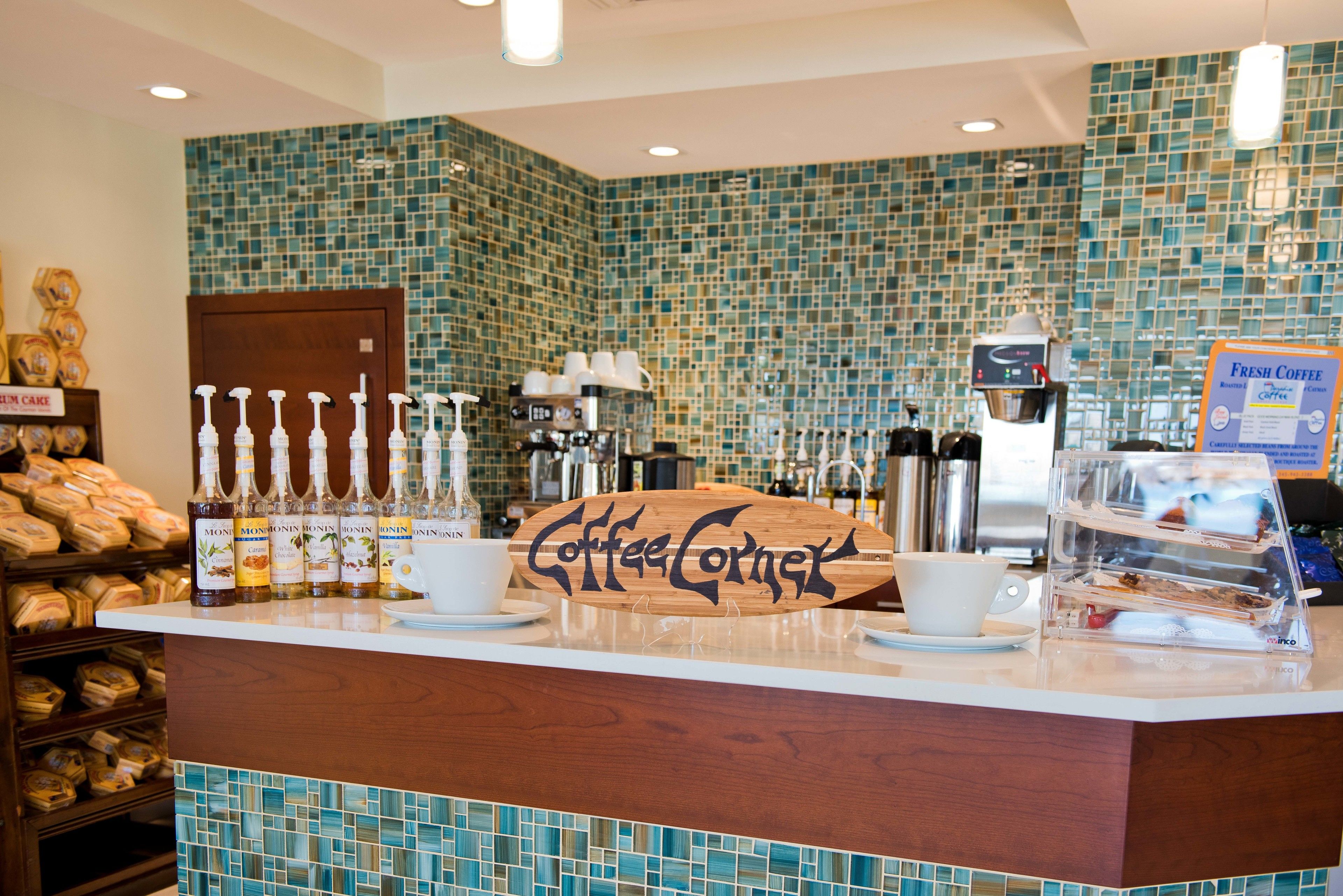 Un bancone di un bar con un cartello che recita 'Coffee Corner', una macchina da caffè e una selezione di chicchi di caffè.