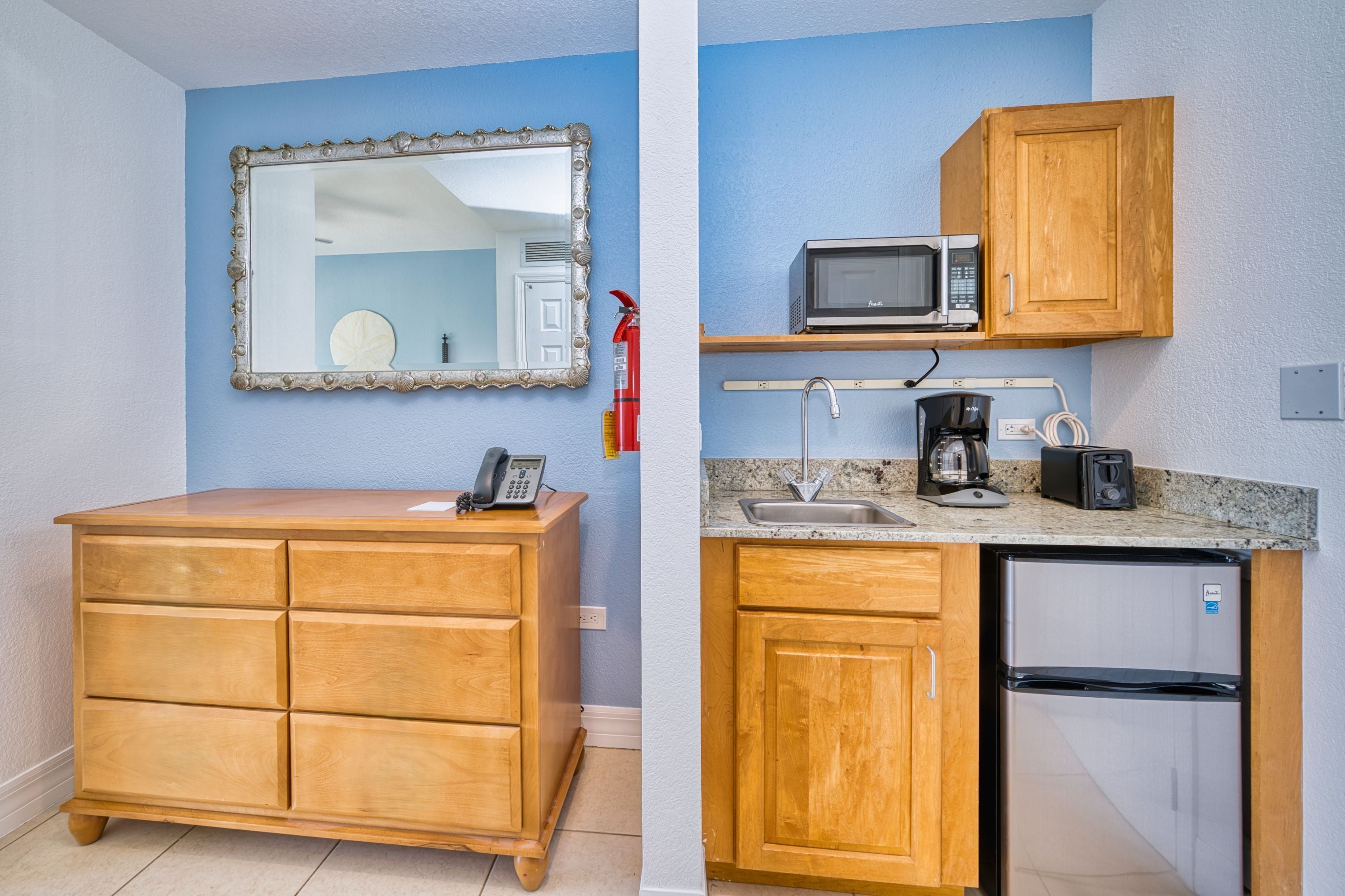 A kitchenette with a microwave, toaster, sink, and refrigerator.