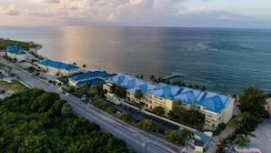 A coastal hotel with multiple buildings, a road, and a view of the ocean. - The Reef Beach Resort - All Inclusive - East End, Grand Cayman (East End)