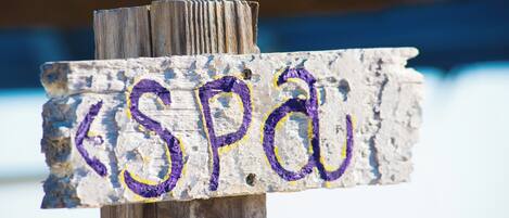 Un letrero de madera con las letras 'SPA' pintadas en morado y amarillo.