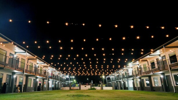 Un hotel de varios pisos, iluminación exterior y un patio central.