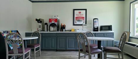 Una pequeña cafetería con una máquina de café, un microondas y un cartel en la pared.